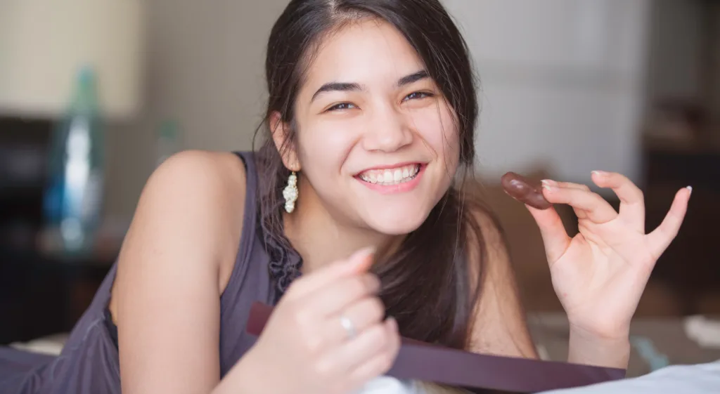 Teen girl holding a piece of chocolate with a smiling face